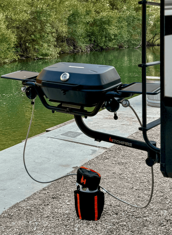 Propane grill tank setup with black carrying case, orange accents and hose.