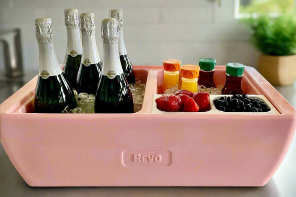Pink coral party cooler bin with “REVO” logo, holding champagne bottles and snacks