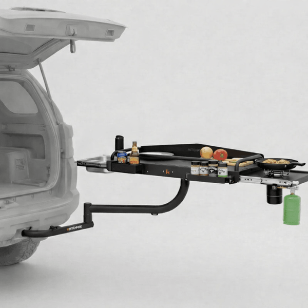 SUV rear cook station with black grill platform, swing arms, and hanging bottle