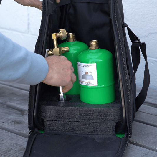 Open black propane carrying case with two green cylinders and brass fittings inside
