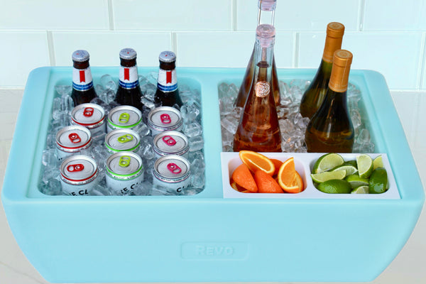 Blue party cooler tub with ice, cans, and bottles, plus fruit and cucumber