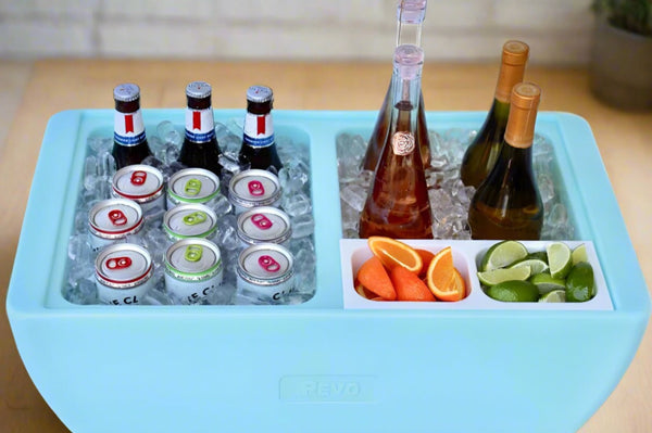 Light blue party cooler with divider holding bottles, ice, orange and cucumber slices