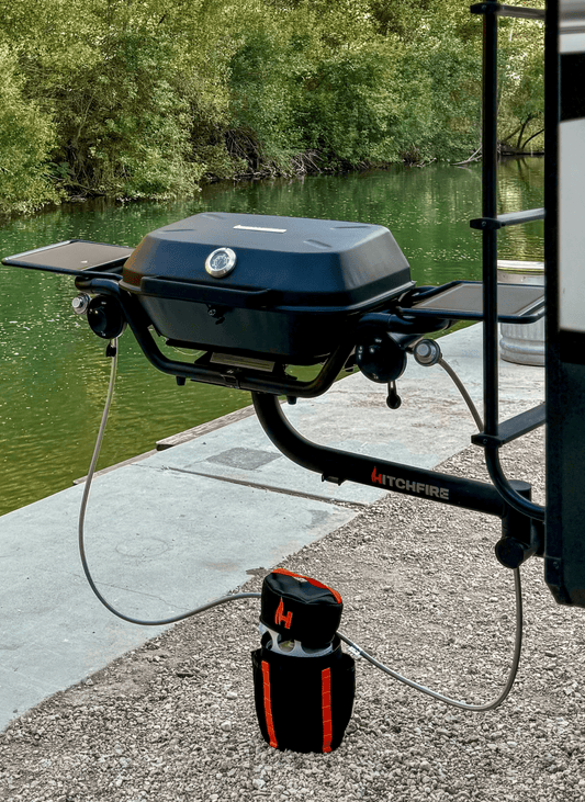 Refillable propane tank with carry case, connected hose, and regulator on grill stand