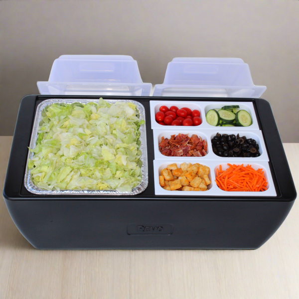Black cooler open with clear food trays holding chopped vegetables and toppings