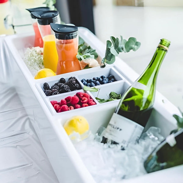 White barge cooler filled with juice cups, bottles, and fresh fruit compartments