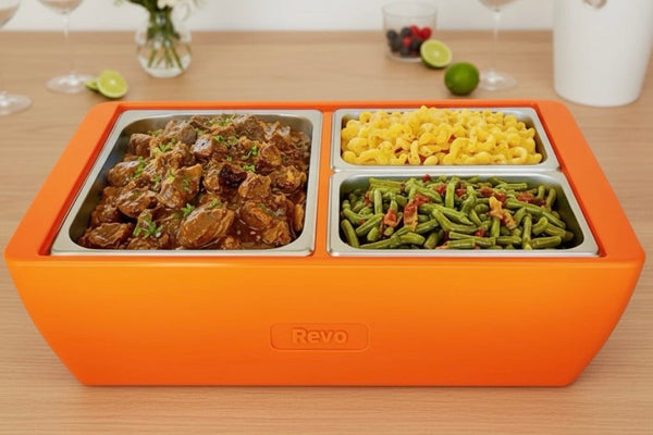 Orange flameless chafer/cooler with two compartments, filled with meat and veggies.
