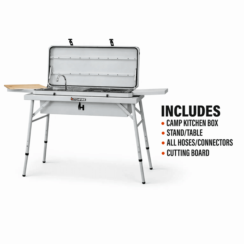Camp kitchen grill with open lid, sink, and metal burner surface on gray table