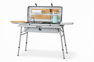 Camp kitchen grill with open lid, sink, and utensil holders on folding legs