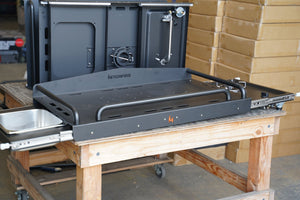 Cook station with HitchFire logo, fold-out grill shelf and side burner controls