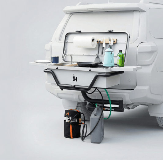 Hitchfire portable hitch grill with open lid, burners, utensils, and drink bottles