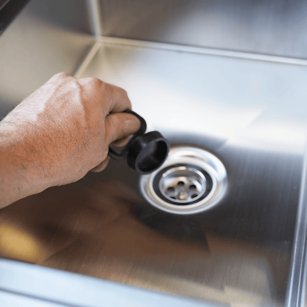 Hand installing sink drain stopper in metal drain opening