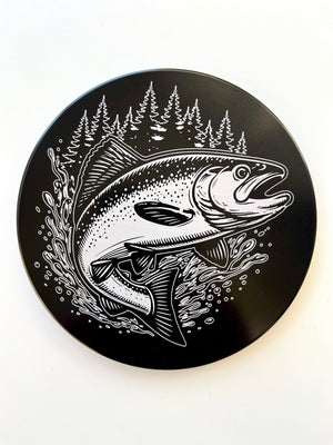 Round hitch cover with king salmon graphic and pine trees illustration on dark background