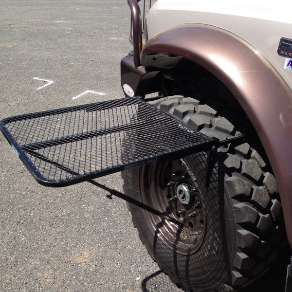 Close-up of large black aluminum camping table with wire mesh top on a spare tire mount