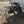 Load image into Gallery viewer, Black steel camping table with wire-mesh top and four legs beside a vehicle
