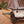 Load image into Gallery viewer, Black steel camping table with wire-mesh top extended from a trailer
