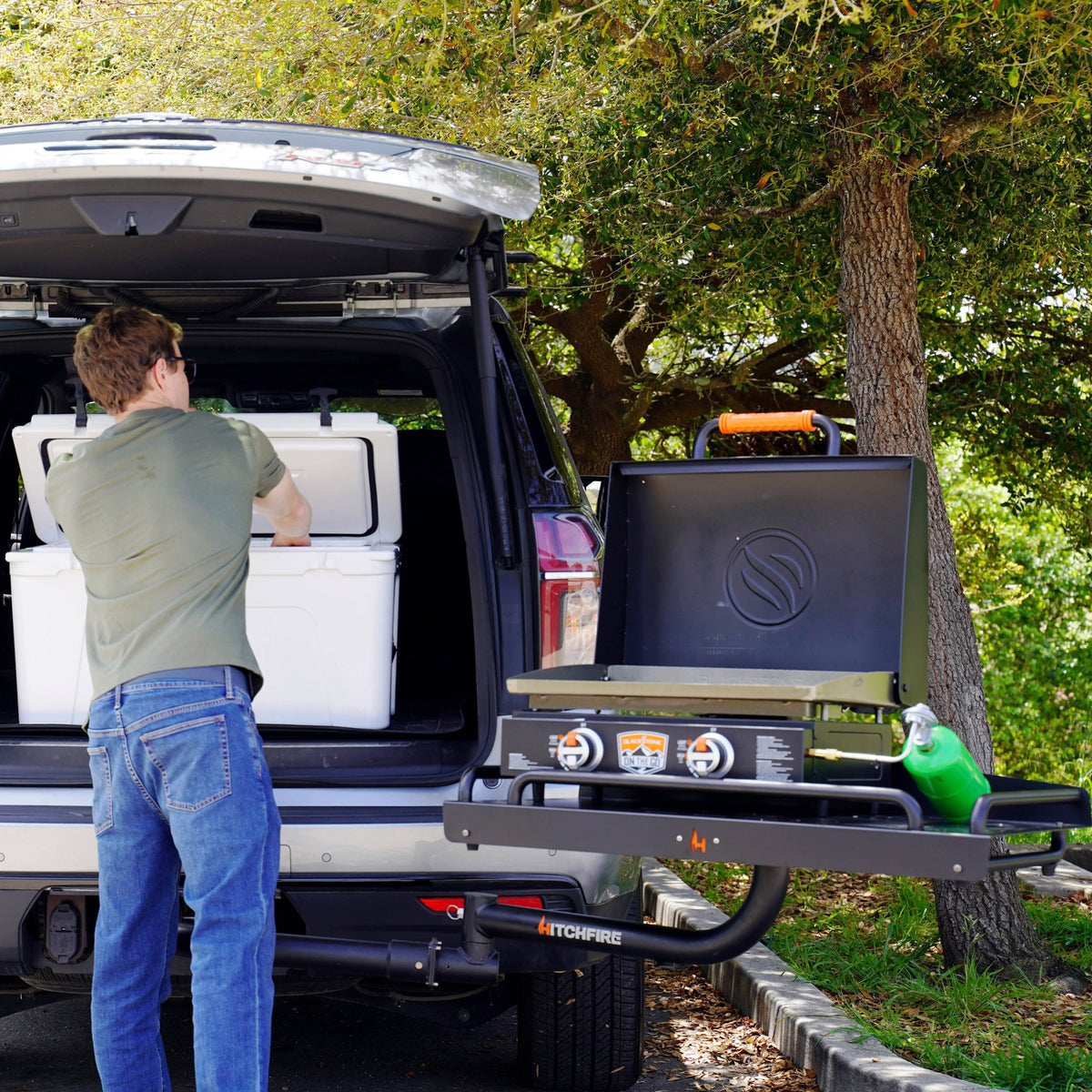 Black swing-out cargo platform extended from vehicle, person loading items onto tray