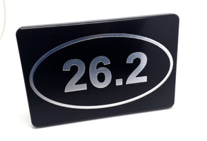 Marathon 26.2 hitch cover in black with a silver oval showing “26.2”