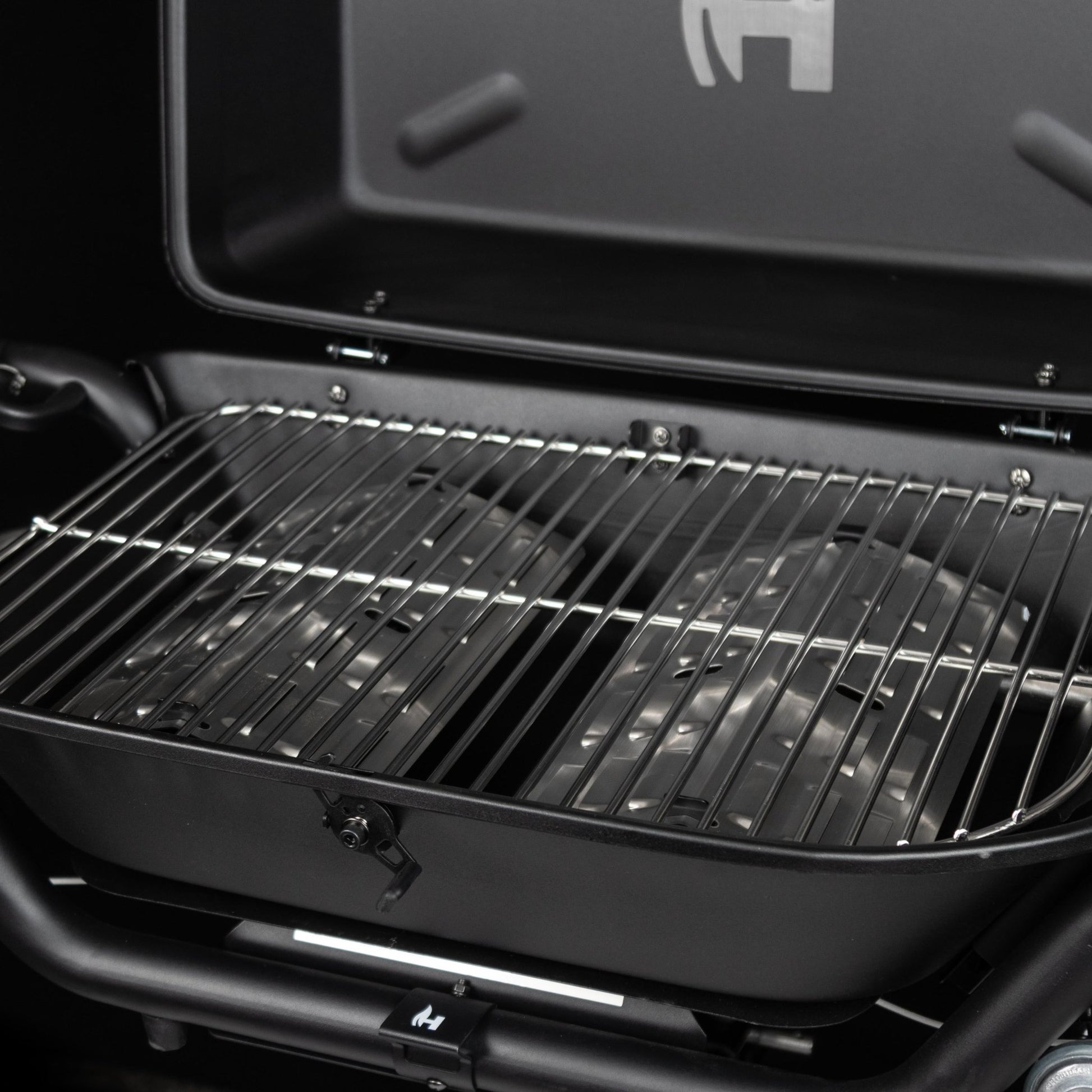 Open black propane grill showing stainless cooking grates and burner area