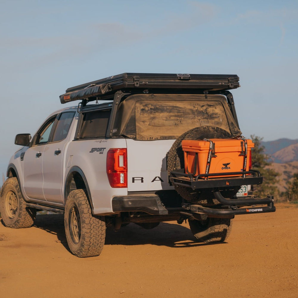 Hitch-mounted swing-away cargo platform with orange storage box on rear of vehicle