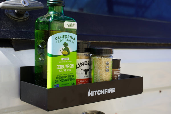 Magnetic spice rack with black shelf holding olive oil bottle and spice jars on truck