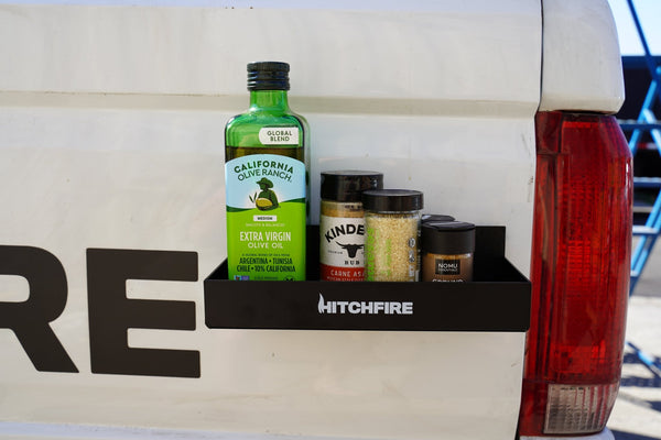 Magnetic spice rack and cupholder with black shelf holding jars and cans on truck