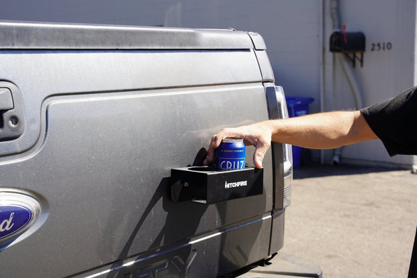 Magnetic cupholder tray, black rack mounted on truck side, hand placing a can