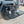 Load image into Gallery viewer, Black aluminum camping table with mesh top and four legs, shown next to a vehicle.
