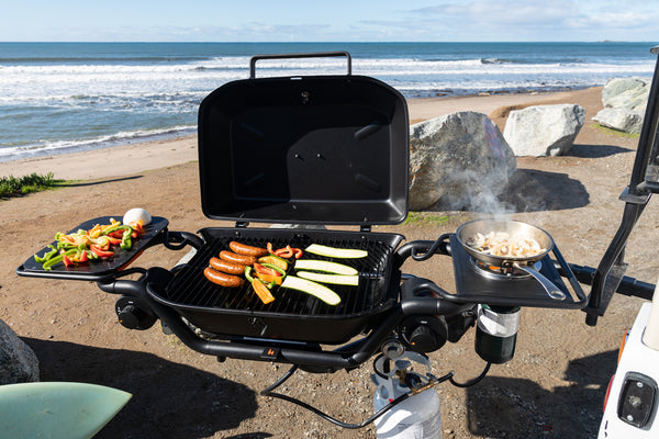 Grilling sausages and vegetables by beach
