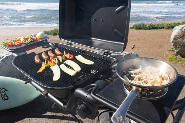 Sausages and vegetables grilling near ocean