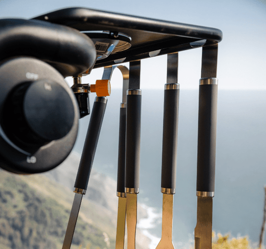 Grilling tool set with black handles and stainless heads near grill