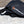Load image into Gallery viewer, Black grill cover with HitchFire logo and strap buckle on stone surface
